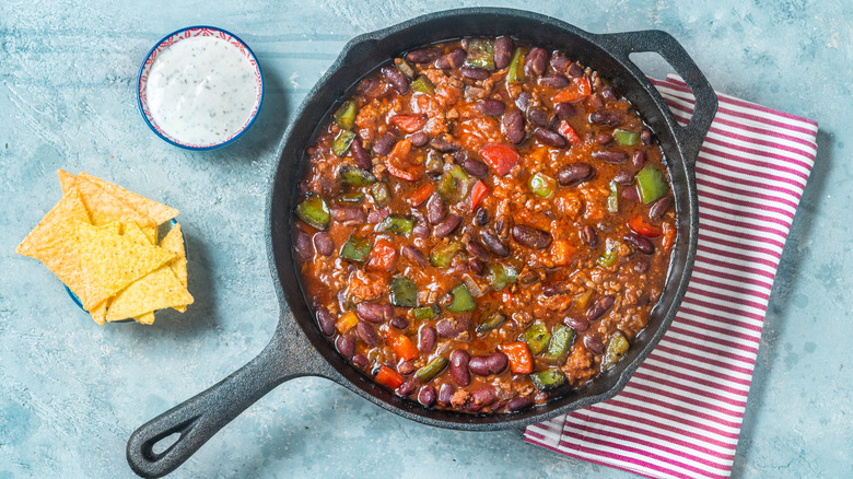 Chili in cast iron pan with side of ranch and tortilla chips.