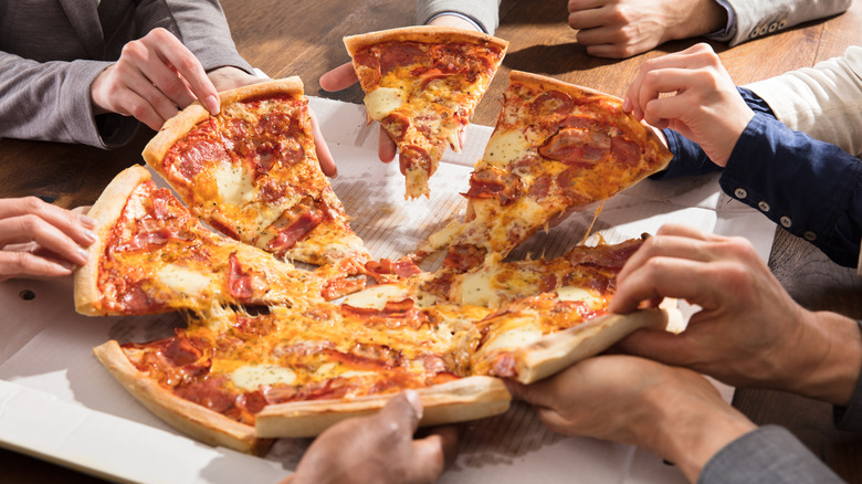 People taking pizza from box