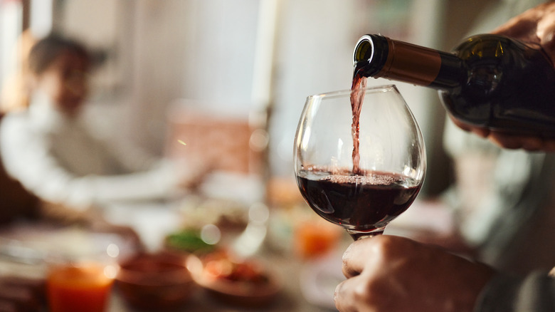 hand pouring wine in glass