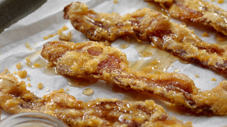 Close-up of maple glazed bacon strips on a parchment-lined pan