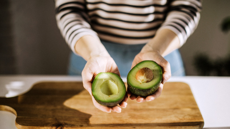 Person holding a halved avocado