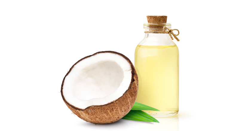 Half a coconut next to a bottle of oil