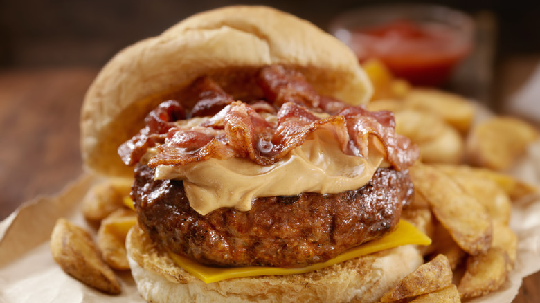 A burger topped with peanut butter and bacon