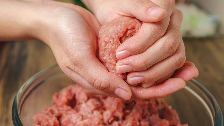 Hands rolling raw beef