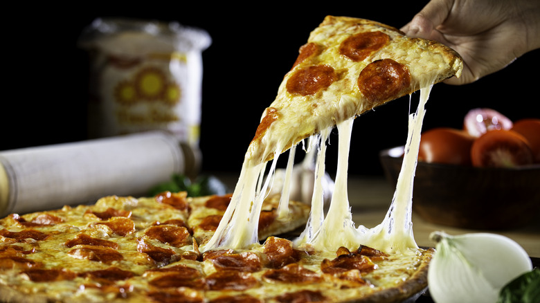 removing slice of pepperoni pizza from pie