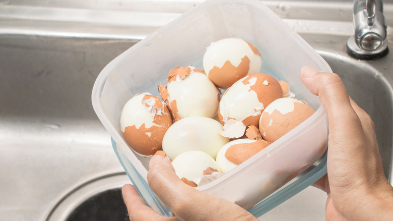 partially peeled hard boiled eggs in a plastic container