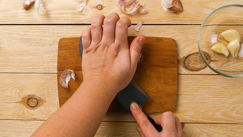 hands crushing garlic with knife