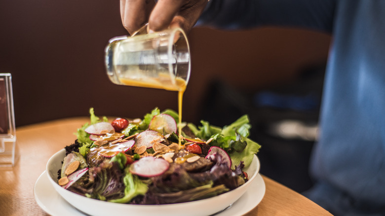 pouring salad dressing over salad