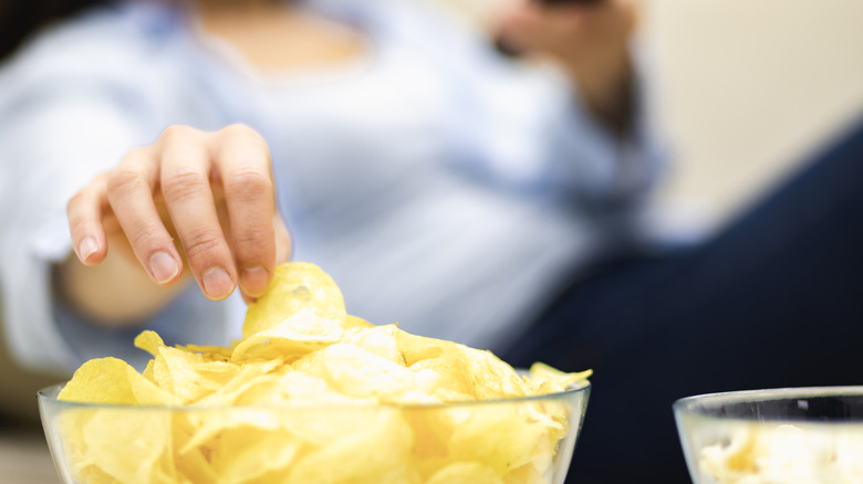 Person on couch grabbing chip