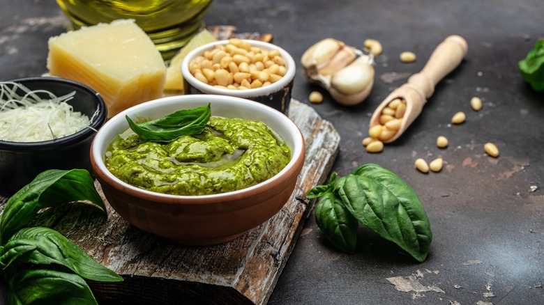 Pesto and ingredients on table with wooden board