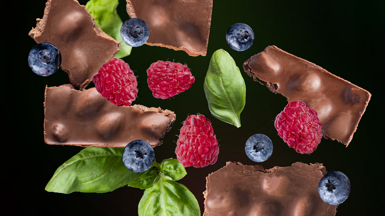 Chocolate, basil, and fruit on black background