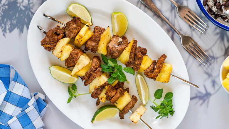 pork and pineapple skewers on plate atop marble kitchen counter