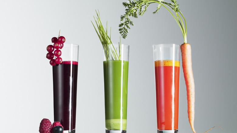 Three glasses of juice in purple, green and orange