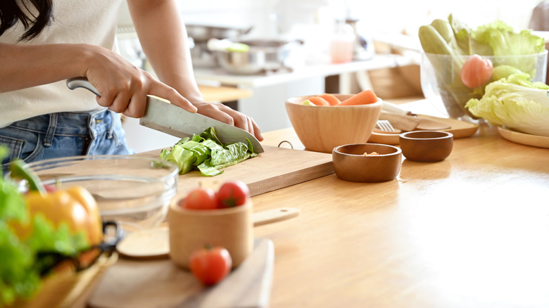 Hand chopping lettuce in kitchen.