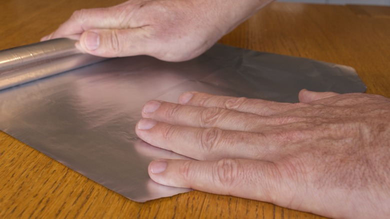 Hands rolling out foil