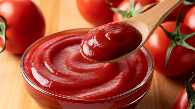Ketchup on wooden spoon and tomatoes