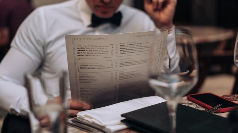 man in formalwear looking at a menu