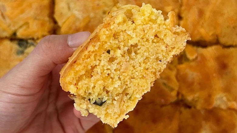 person holding a piece of kimchi cornbread