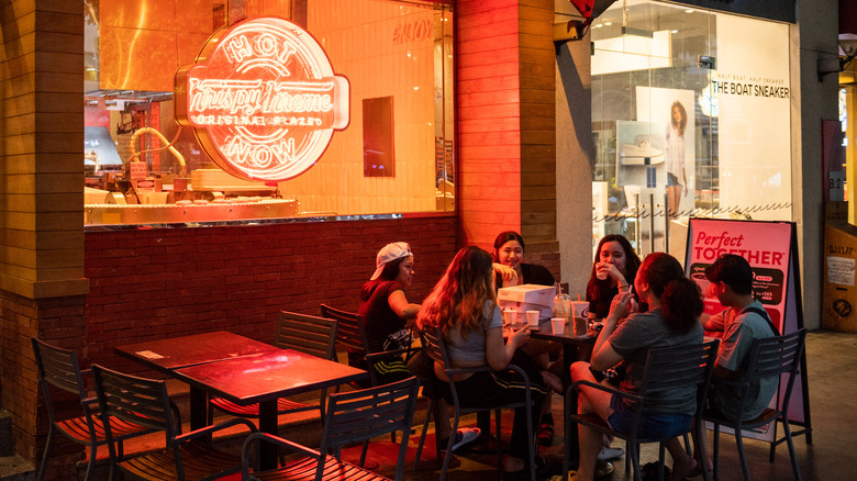 Friends eating at table in front of Krispy Kreme