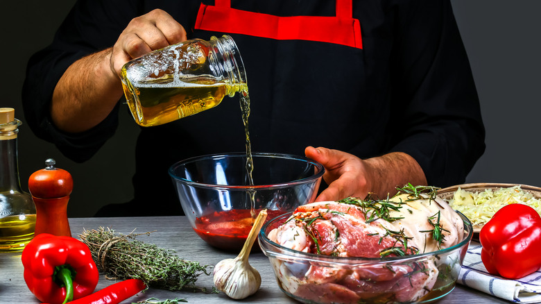 a man pouring a beer into a marinade with meats on a table