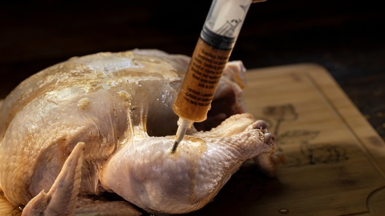 Injecting a chicken with a marinade