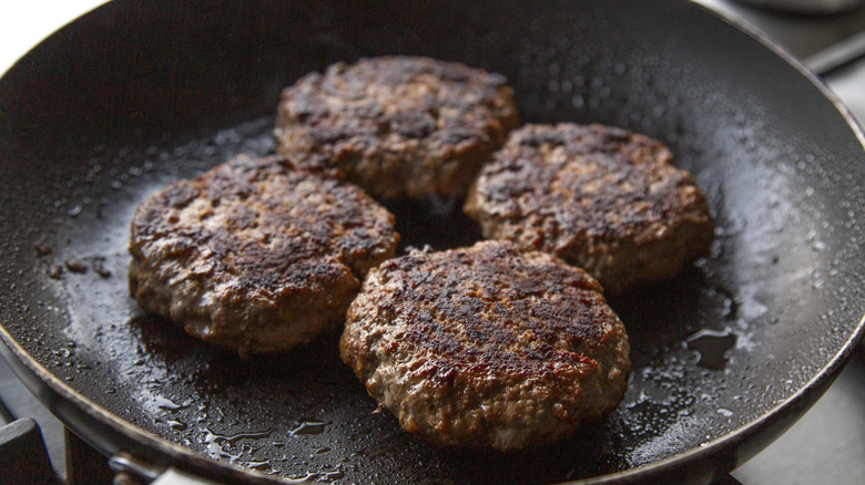 burgers frying in a pan