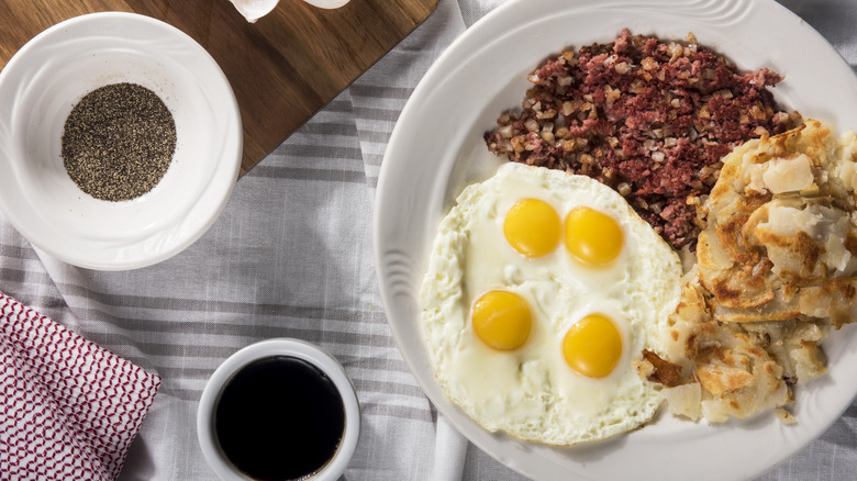 Meatloaf hash and fried eggs on plate at breakfast table