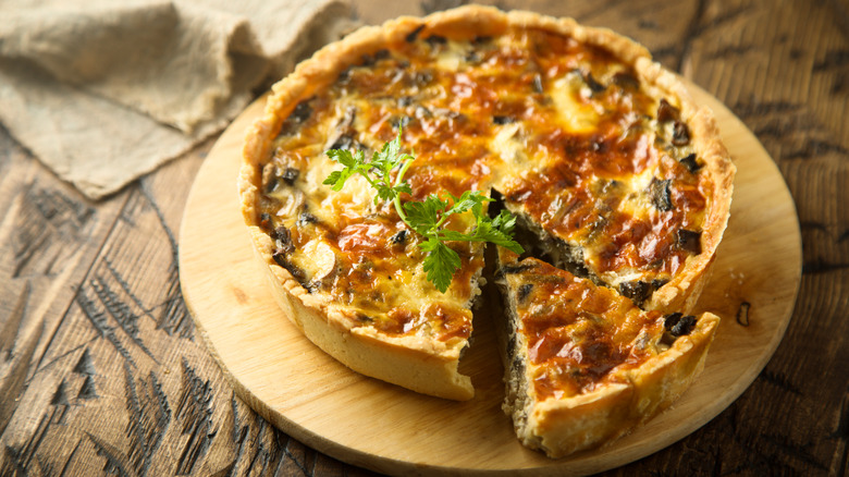 Quiche on wooden table with wedge piece