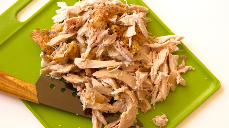 Shredded rotisserie chicken on a chopping board