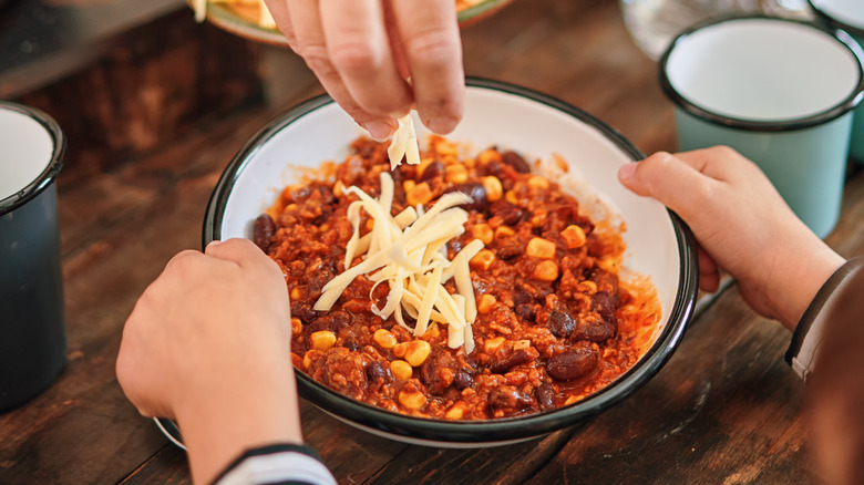 sprinkling cheese on chili