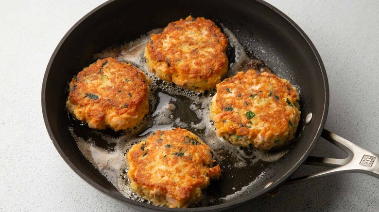 Cooked salmon patties in a black frying pan