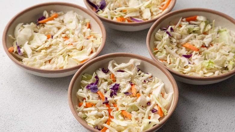 Four beige bowls filled with coleslaw mix