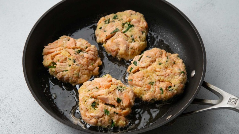 Uncooked salmon patties in a black frying pan