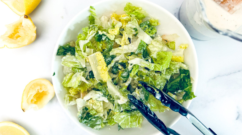 tossing lettuce with Caesar dressing