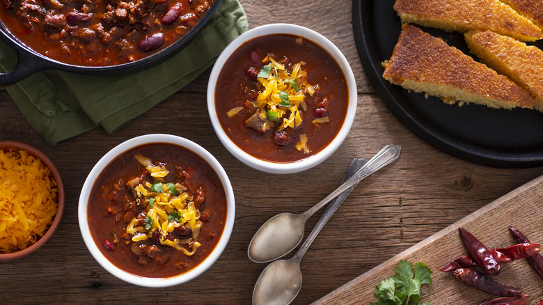 Two bowls of chili topped with shredded cheese