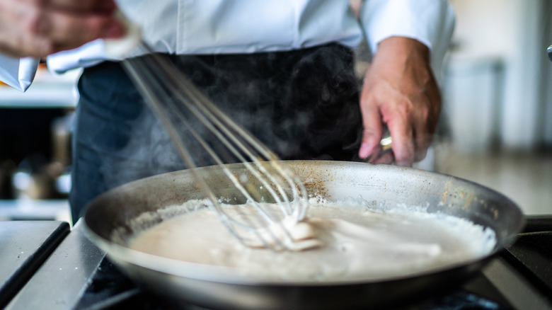 person whisking butter sauce in a pan