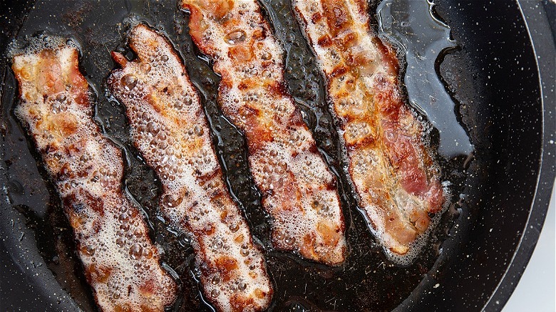 Sizzling bacon in a black pan