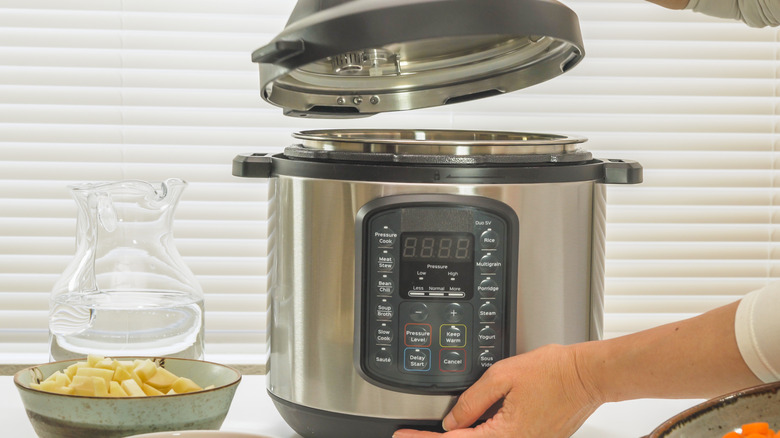 Slow cooker with a person lifting up the lid