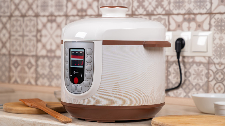 Clean, white slow cooker plugged in and sitting on counter