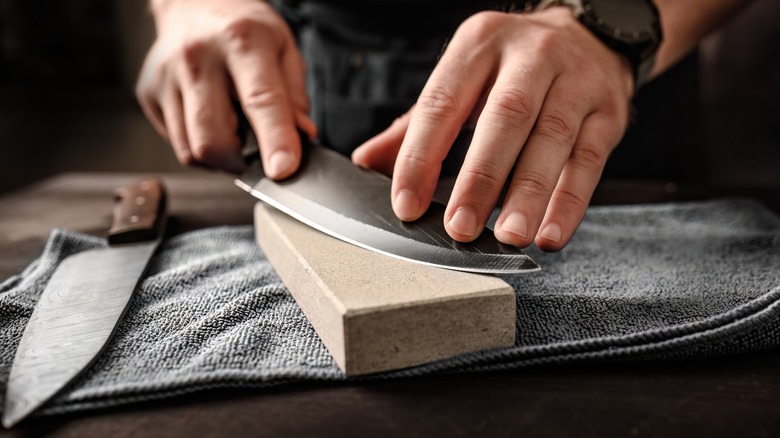 Hands sharpening a knife on a block