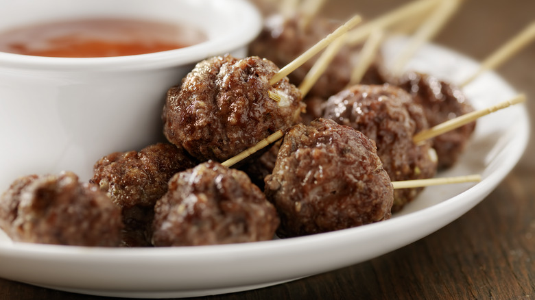 Meatballs on platter with dipping sauce in background