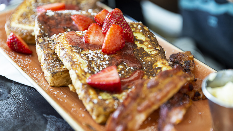 French toast on a plate topped with strawberries.