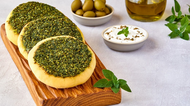 Manakish topped with za'atar served with olives and a sauce