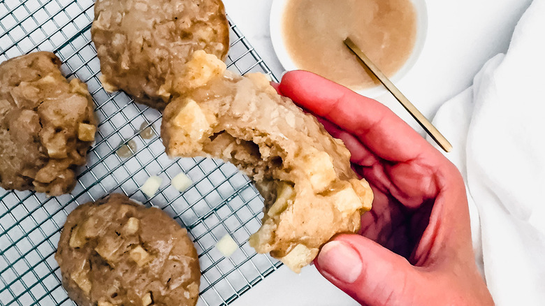 holding apple fritter with bite taken out