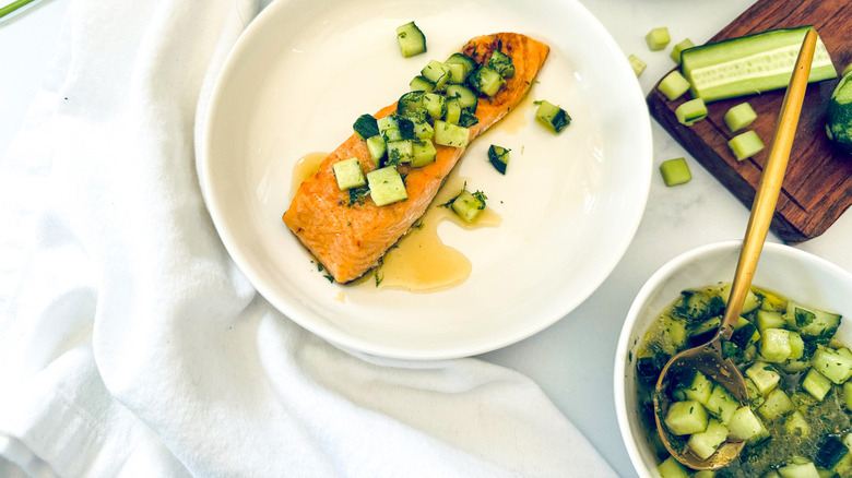 salmon with cucumber topping on white plate