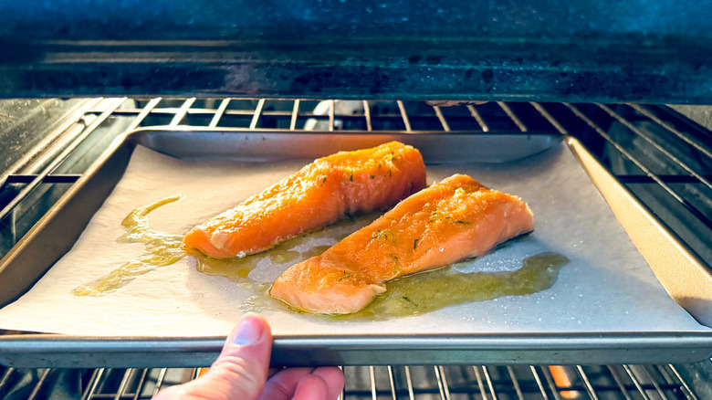 hand putting salmon fillets into oven