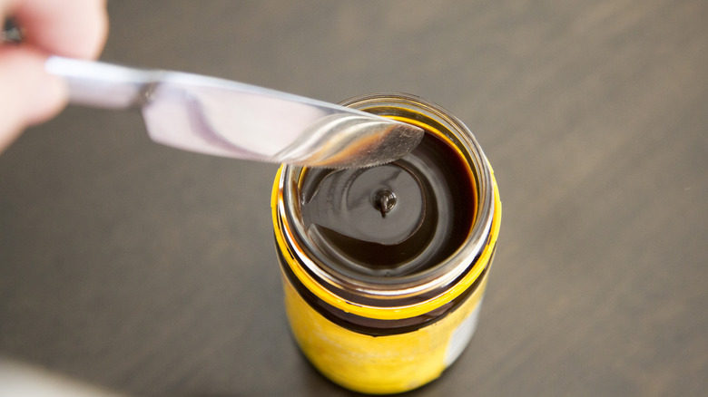 putting butter knife into opened jar of marmite