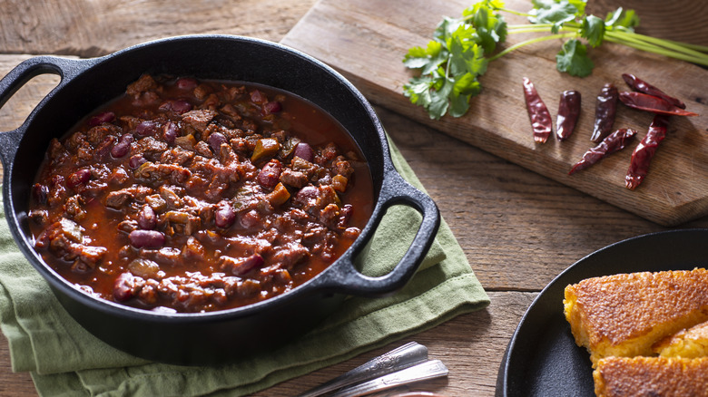 pot filled with chili next to other ingredients