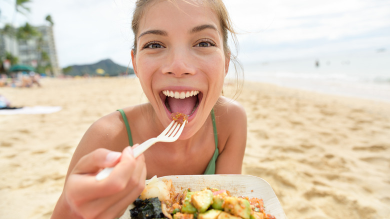 woman eating on beach