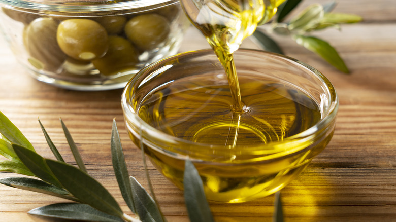 olive oil and fresh herbs on table with olives